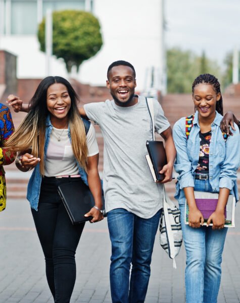 Group of five african college students spending time together on campus at university yard. Black afro friends studying. Education theme.