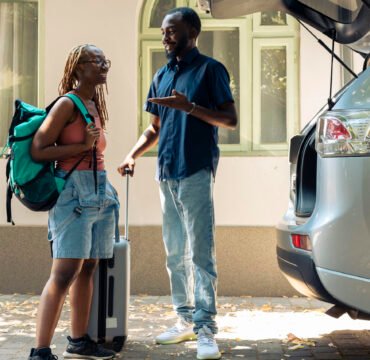 service premuim transfert AIBD African american couple travelling by car, putting luggage and baggage in trunk to leave on summer holiday. People in relationship going on vacation trip with trolley and travel bags.